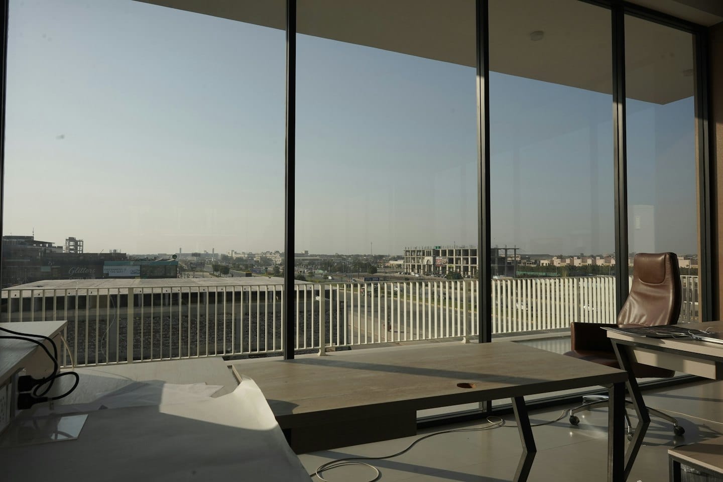 Modern office with desk and chair by large windows overlooking city.