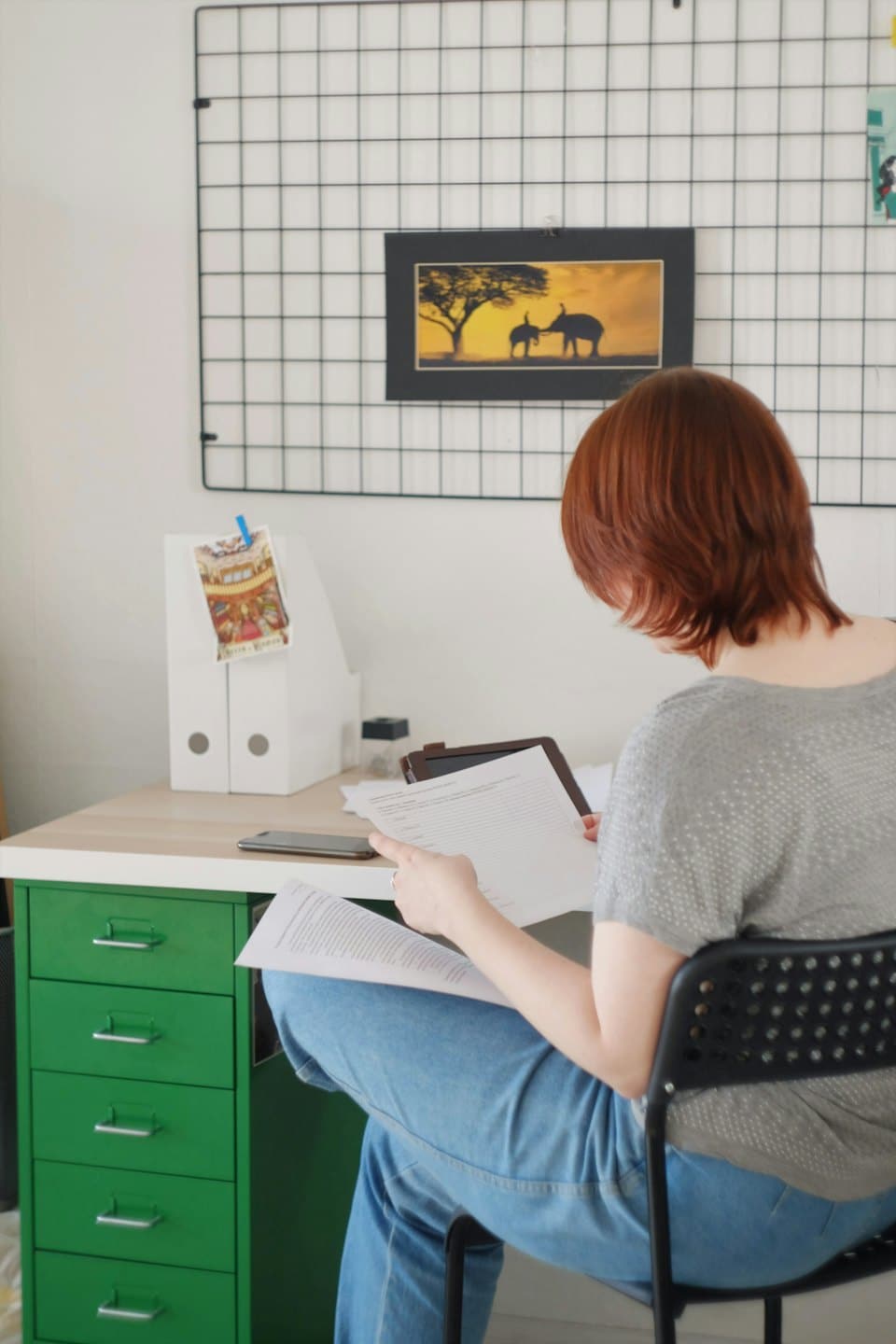 Person reviews documents at a light wood desk with tablet.