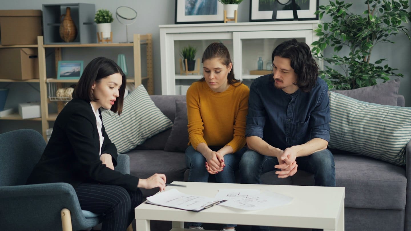 Professional discusses documents with a couple in a modern office.