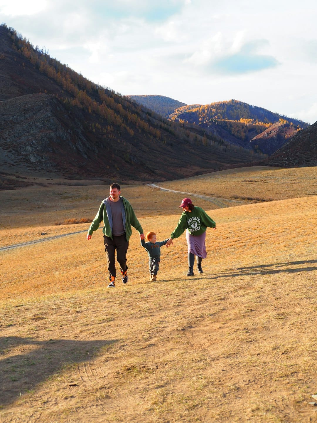 Family walking hand in hand across a mountain valley meadow.